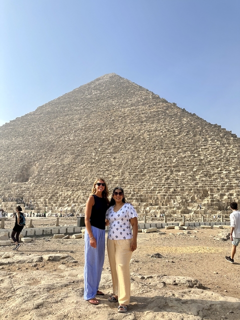       Two women standing with the Great Pyramid of Giza in the background.
  
