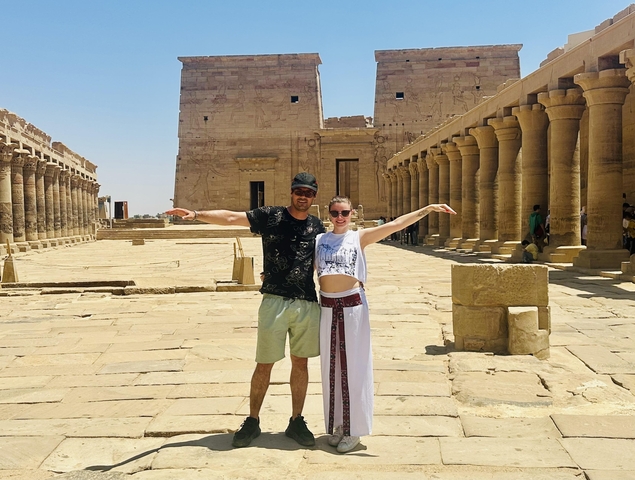 Two people posing with exaggerated poses in an ancient temple courtyard.