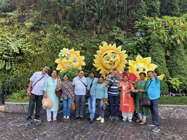 Group photo with people standing in front of decorative sunflowers.