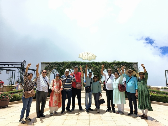 Group of tourists with hands raised in a scenic outdoor setting.