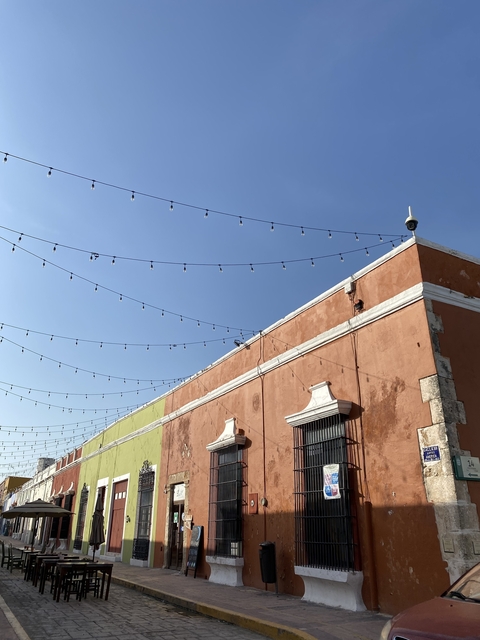 Orange building with white decorative elements and string lights against a clear blue sky.