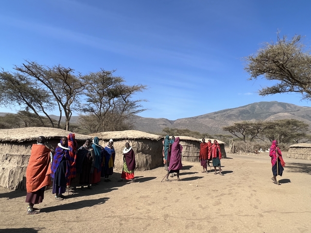       Group of people in traditional attire in a rural setting.
  