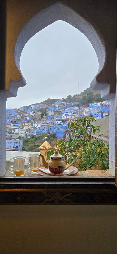 View from a window with tea set overlooking blue city buildings.
