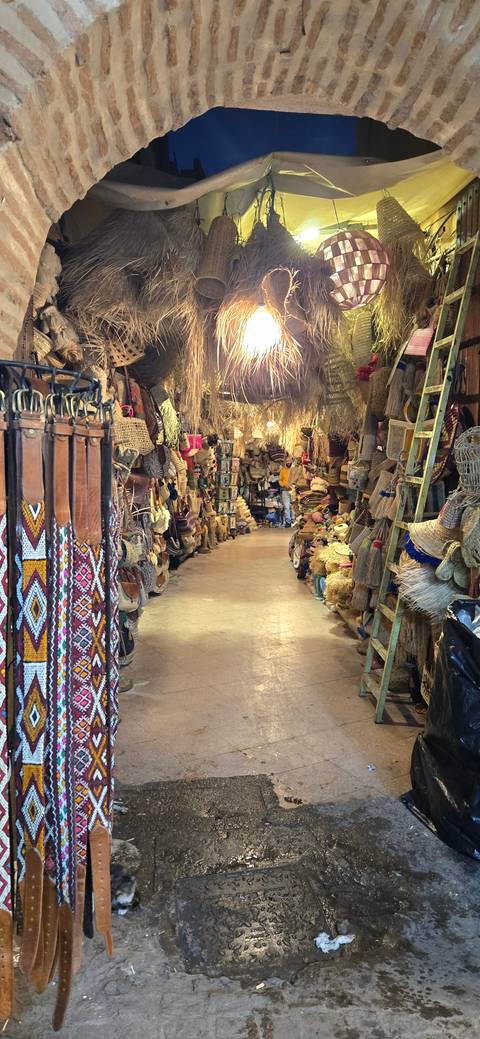       Colorful market full of woven baskets and belts.
  