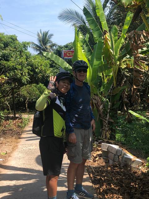 Two cyclists posing in a tropical setting.
