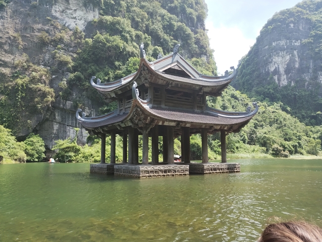 A floating pavilion with a mountainous backdrop.
