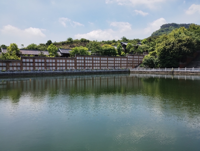 A calm pond reflecting surrounding architecture and greenery.