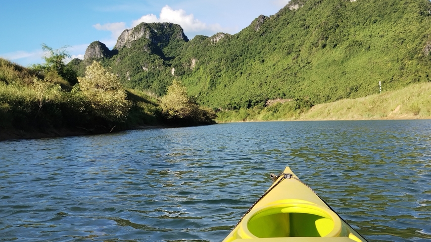A kayak on a scenic river surrounded by lush green mountains.