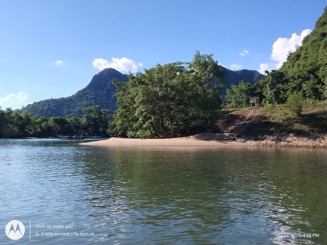 A serene river scene with a sandy shore and trees.