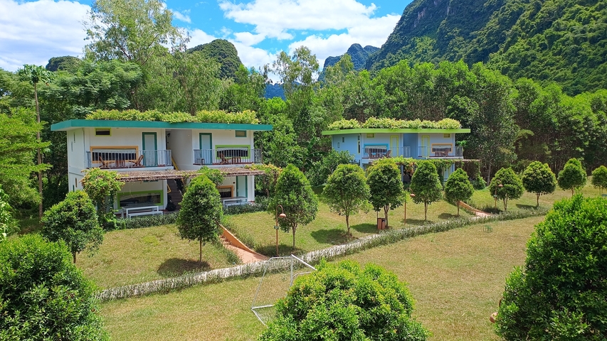 Two modern villas surrounded by a lush green garden.