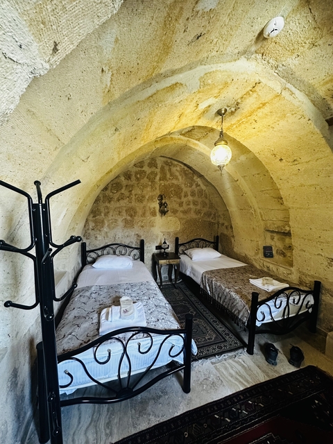       Stone-walled room with two single beds and an arched ceiling.
  