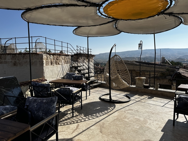       Rooftop patio with wicker chairs and tables, panoramic mountain views.
  