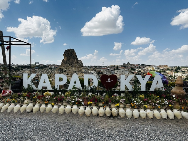       Panoramic view of Cappadocia with a prominent sign.
  