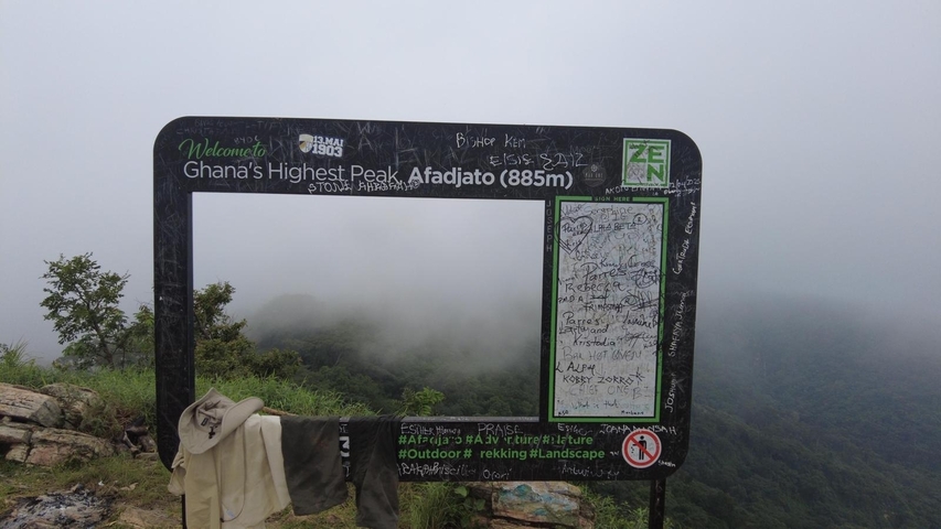A welcome sign at Ghana's highest peak with foggy surroundings.