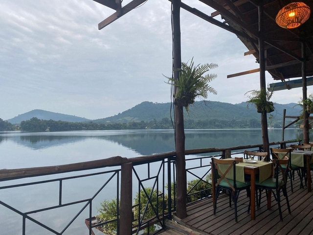 A lakeside view with a restaurant and mountains in the distance.