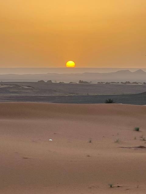 Sunset over rolling sand dunes in the desert.