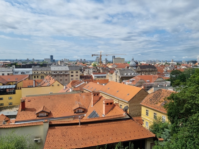 Cityscape featuring rooftops and a distant crane.