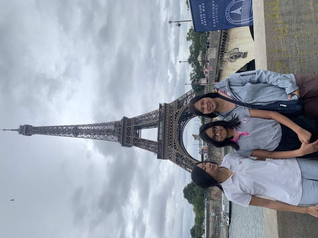       Three people posing in front of the Eiffel Tower.
  