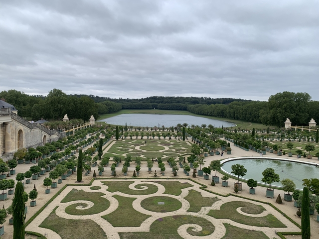       Gardens with a lake and neatly trimmed bushes and trees.
  