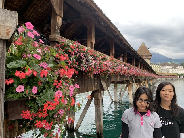       Two people posing on a flower-covered wooden bridge.
  