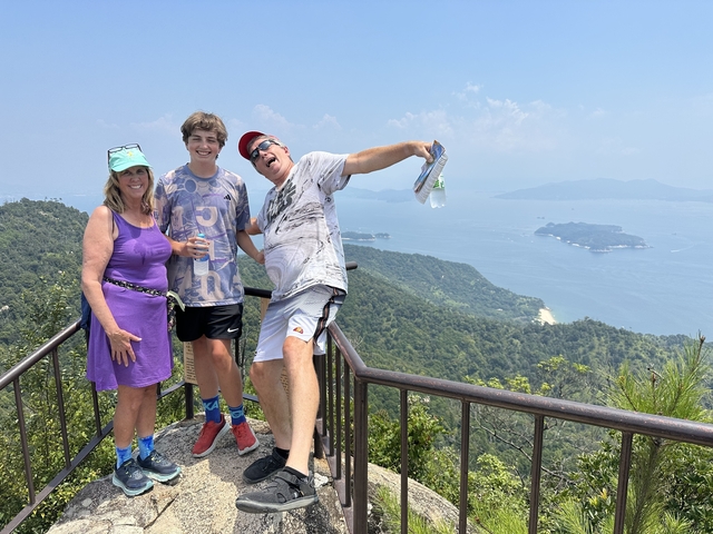       Family posing on a lookout point with sea and islands in the background.
  