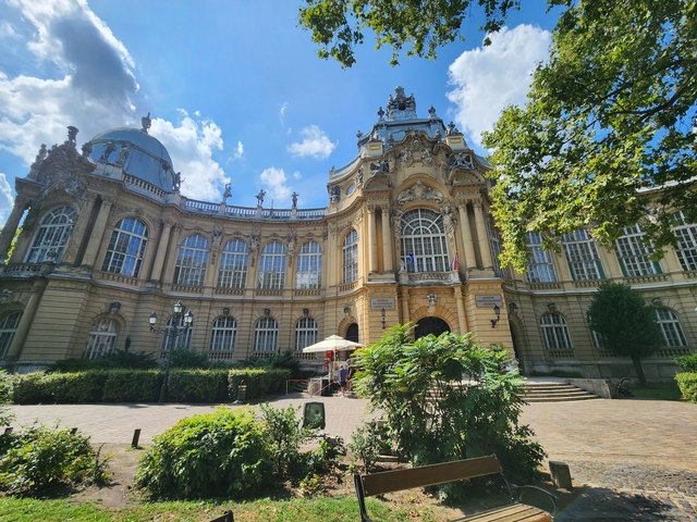       An ornate neoclassical building with columns and gardens.
  