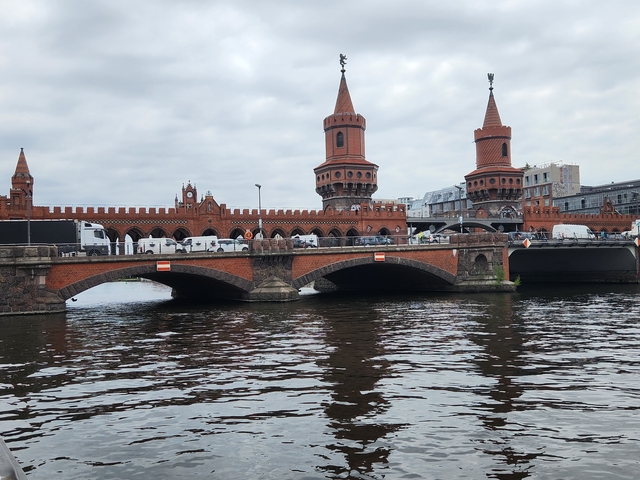       A red brick bridge with towers spanning a river.
  