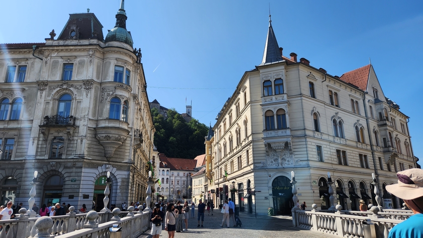       Crowded urban scene with historic architecture and a castle in the distance.
  