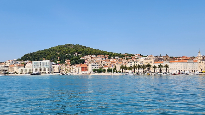       A panoramic view of a coastal city with a hill in the background.
  