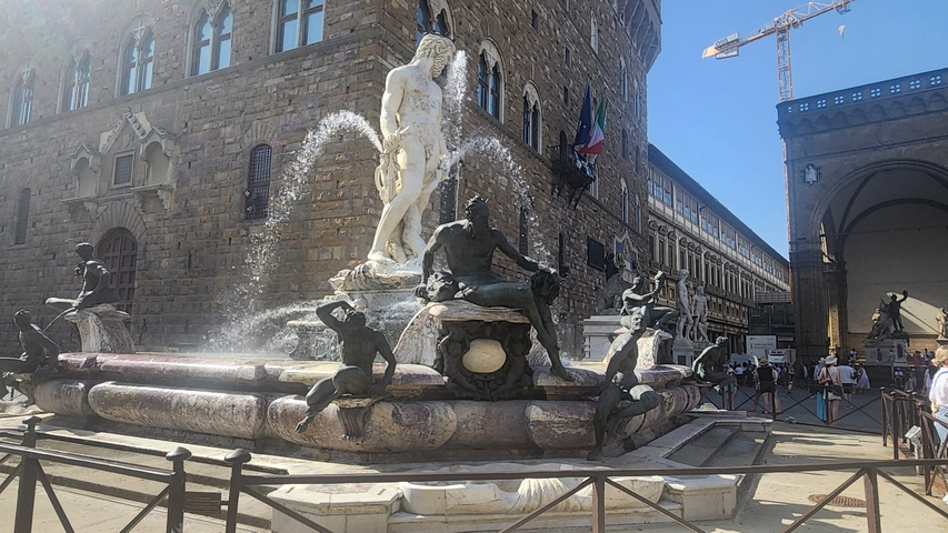       A famous fountain in a city square, surrounded by buildings and people.
  