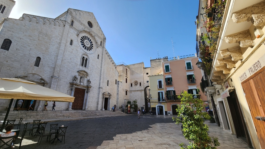       A medieval stone building in an empty square under clear skies.
  