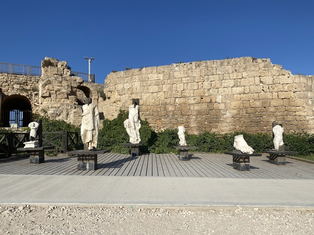 Ancient stone sculptures displayed in front of a stone wall.