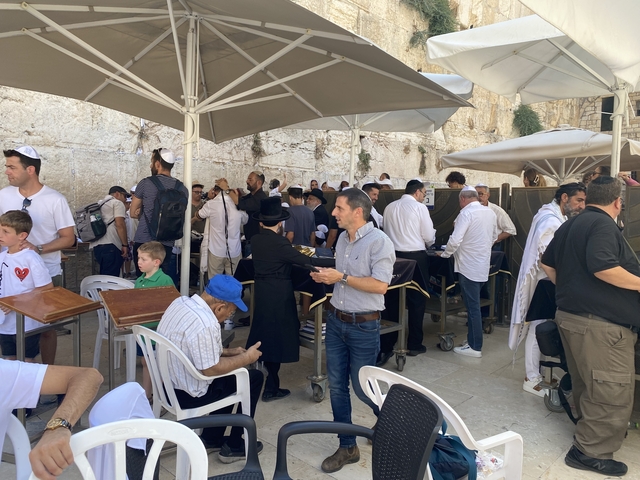 People gathered at a prayer site with parasols and chairs.
