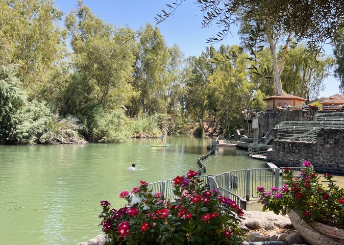       Scenic river view with people enjoying the water surrounded by trees.
  