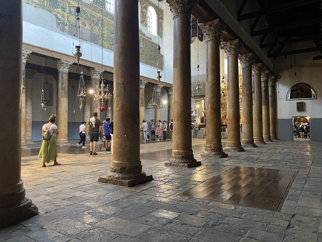       Interior of an ancient stone building with people walking around.
  
