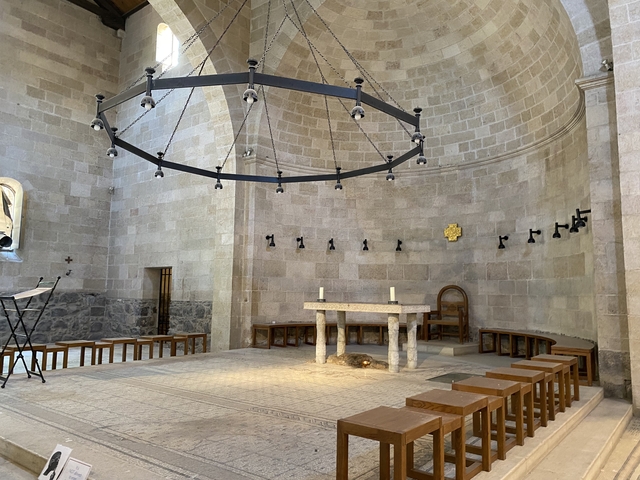       An interior of a stone-built church with chairs and a chandelier.
  