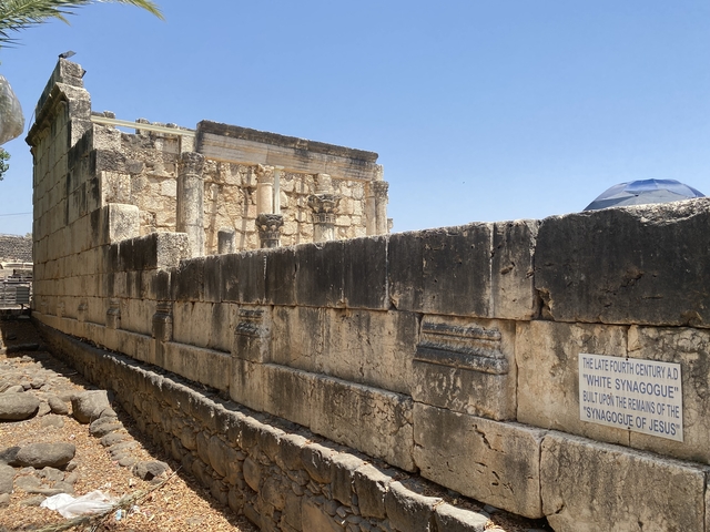       Ancient stone ruins with a wall and an informative sign.
  