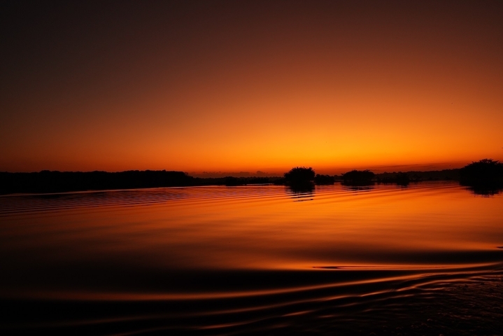 Stunning view of a sunset over a calm river with a striking orange sky.