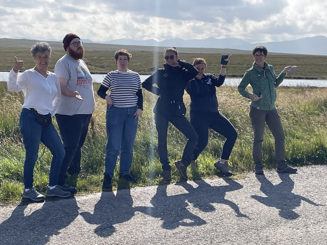       Group of people posing joyfully in an open field.
  