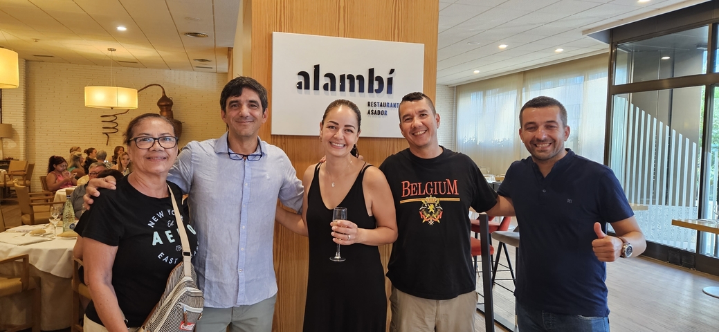 Five people posing inside a restaurant named 'alambi'.