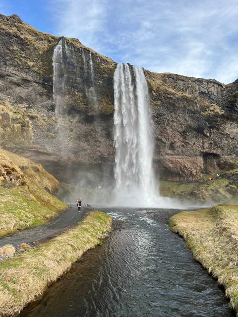       Waterfall flowing over rocky terrain into a valley.
  