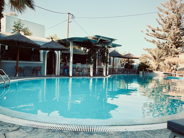 A poolside with lounge chairs and umbrellas under clear skies.