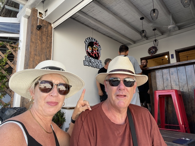 Couple sitting in a cafe with humorous rooster sign.