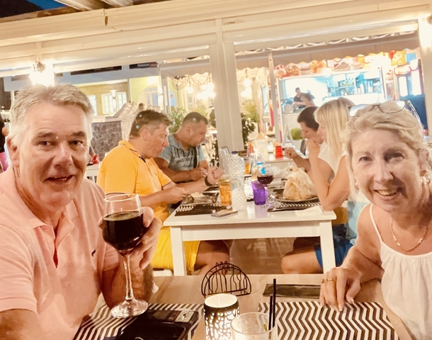       Couple dining at a restaurant, smiling at the camera.
  