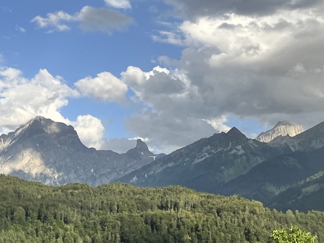       Mountain peaks with blue sky and clouds.
  