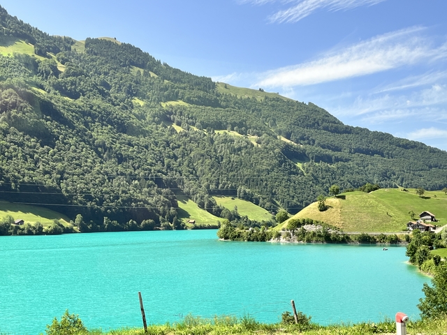       Turquoise lake surrounded by lush green hills.
  