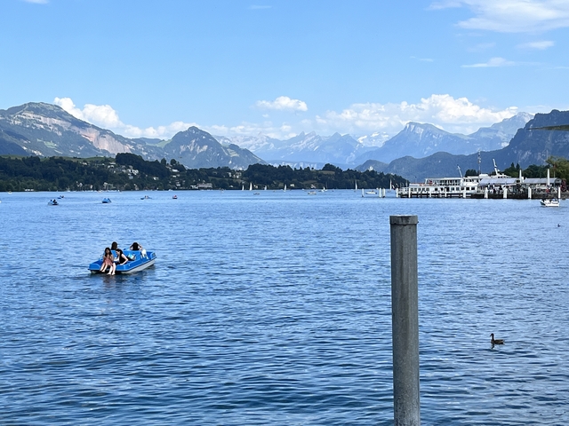       People boating on a lake with mountain views.
  