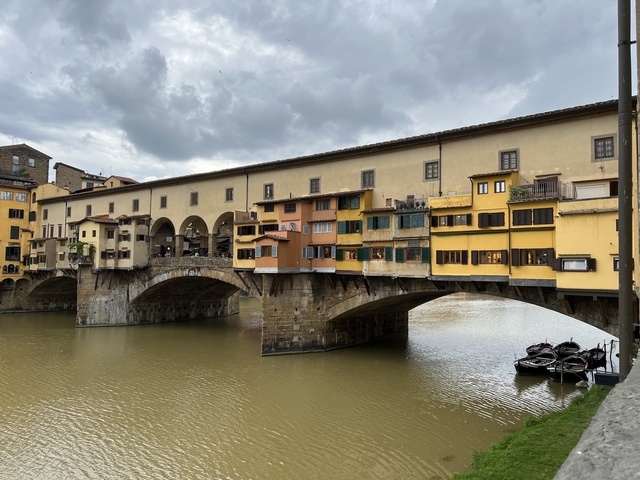       Ponte Vecchio in Florence over a river with boats.
  