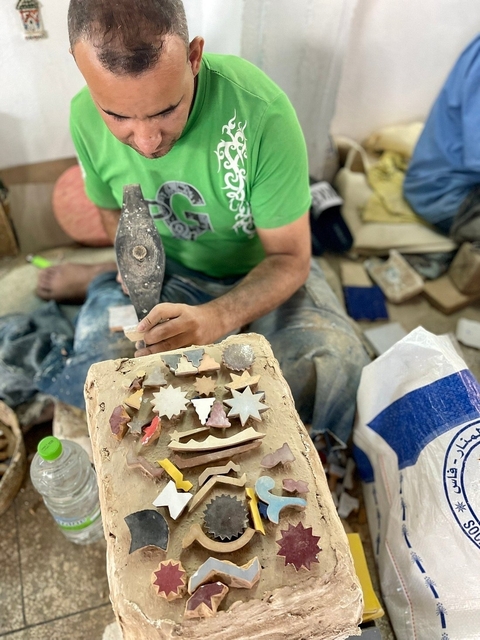 An artist shaping metal pieces with a hammer.