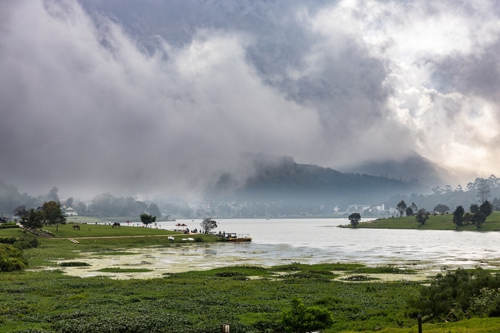       A serene lakeside with mist over the mountains.
  
